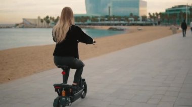 Güzel sarışın kadın denize yakın elektrikli bisiklet sürüş.