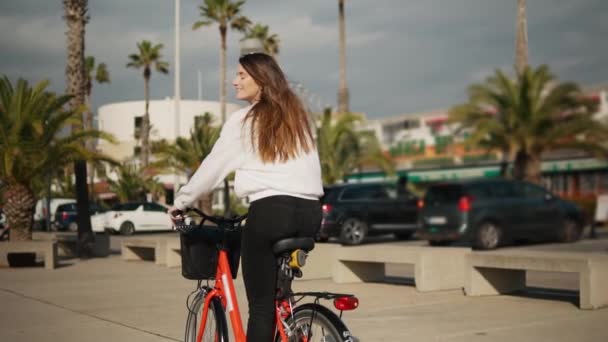 Junge Frau oder Mädchen, die mit dem Fahrrad neben Palmen strampeln — Stockvideo