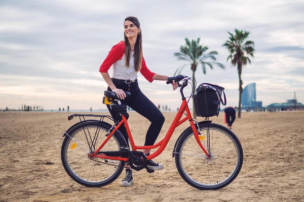 Жінка їде на велосипеді уздовж пляжного піску в літній час — стокове фото