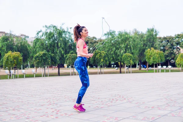 Ajuste mulher bonita com corda de salto em um parque — Fotografia de Stock