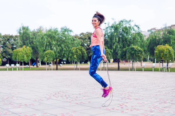 Ajuste hermosa mujer con saltar la cuerda en un parque — Foto de Stock