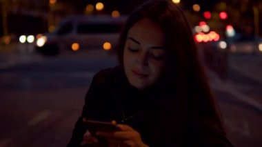 Çekici kadın cep telefonuyla gece sokakta oturan