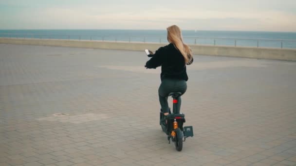 Красивая блондинка за рулем электрического велосипеда у моря . — стоковое видео