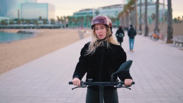 Mujer rubia bonita conduciendo bicicleta eléctrica cerca del mar . — Vídeos de Stock