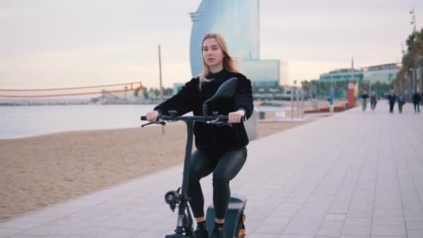 海の近くの電動自転車の運転かなりブロンドの女性. — ストック動画