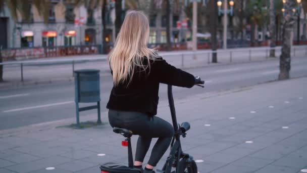 Hübsche blonde Frau fährt Elektro-Fahrrad in der Stadt — Stockvideo