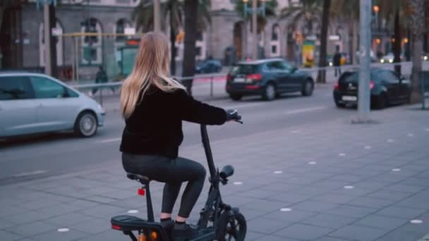 Mujer rubia bonita conduciendo bicicleta eléctrica en la ciudad — Vídeos de Stock