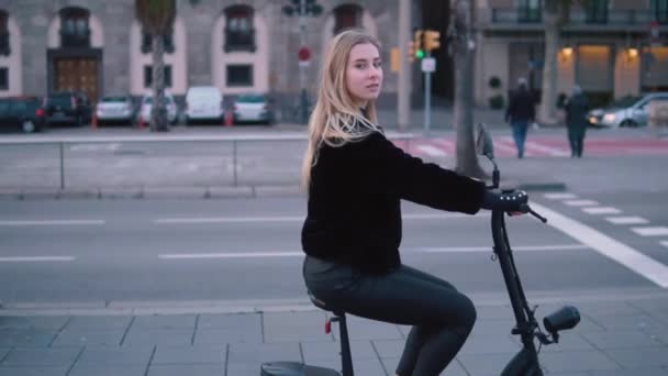 Mujer rubia bonita conduciendo bicicleta eléctrica en la ciudad — Vídeo de stock