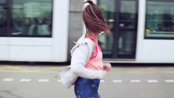 Γυναίκα που τρέχει στο δρόμο της πόλης με κτίρια στο παρασκήνιο — Αρχείο Βίντεο