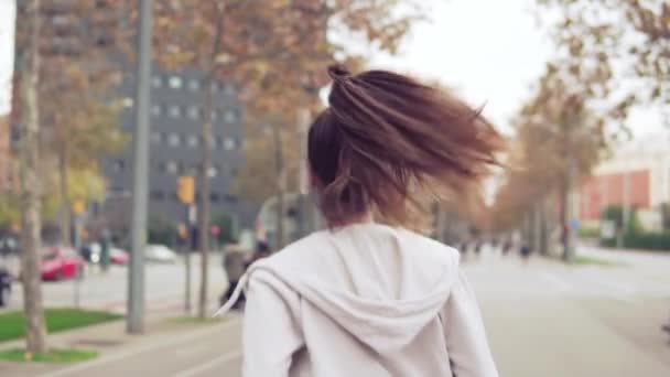 Mujer corriendo en la calle de la ciudad con edificios en el fondo — Vídeos de Stock