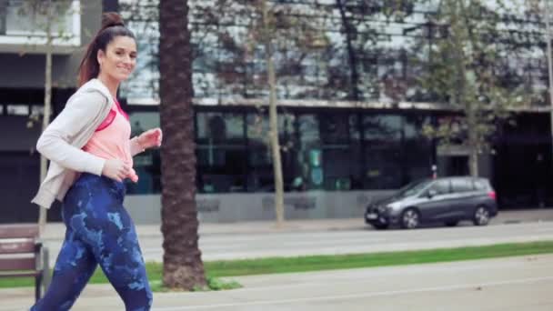 Mujer corriendo en la calle de la ciudad con edificios en el fondo — Vídeo de stock