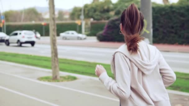 Mujer corriendo en la calle de la ciudad con edificios en el fondo — Vídeo de stock