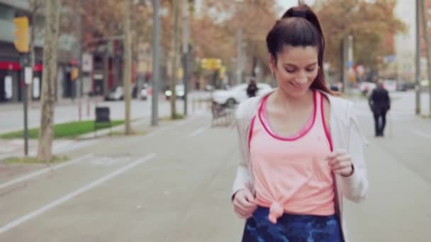 Mujer corriendo en la calle de la ciudad con edificios en el fondo — Vídeos de Stock