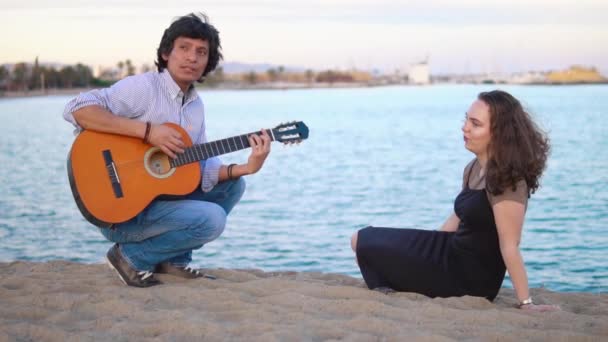 Красива пара музикантів сидить уздовж пірсу біля моря — стокове відео