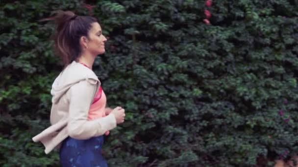 Vídeo en cámara lenta de una mujer en forma corriendo por el parque. entrenamiento deportivo — Vídeos de Stock