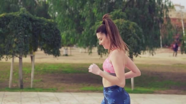 Vídeo en cámara lenta de una mujer en forma corriendo por el parque. entrenamiento deportivo — Vídeos de Stock