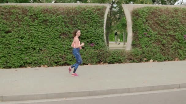 Vídeo en cámara lenta de una mujer en forma corriendo por el parque. entrenamiento deportivo — Vídeos de Stock