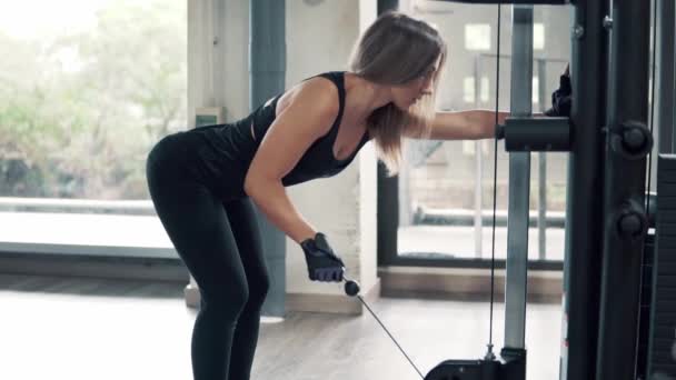 Skott av ung passar kvinna gör triceps övning använder utbildning maskin i gymmet — Stockvideo