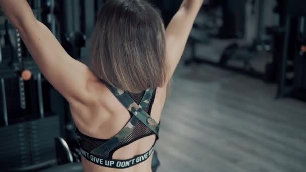 Снимок молодой пригодной женщины делает плечи упражнения с помощью тренажера в тренажерном зале — стоковое видео
