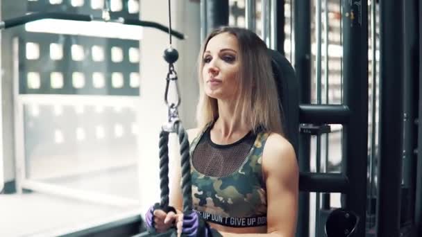 Skott av ung passar kvinna gör triceps övning använder utbildning maskin i gymmet — Stockvideo