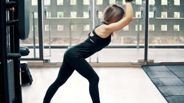 Záběr z mladých fit žena dělá triceps cvičení pomocí stroj tréninku v tělocvičně — Stock video