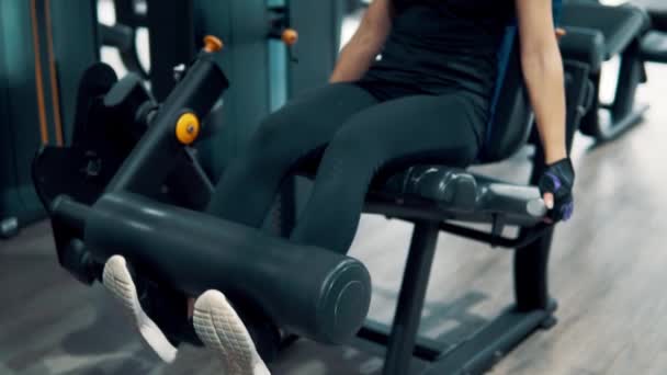 年轻的健康女性在健身房使用训练机做腿部运动 从前面看 — 图库视频影像