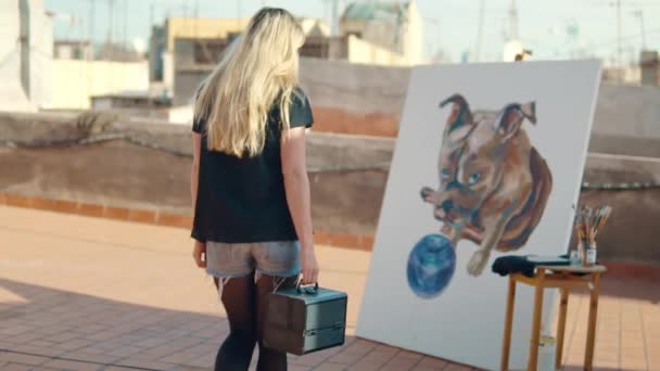 Молода жінка малює художника на даху будинку — стокове відео