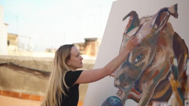 Молодая женщина рисует на крыше дома — стоковое видео