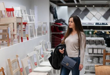 Genç güzel kadın kendini yeni mobilya, Ahşap sandalyeler bulma