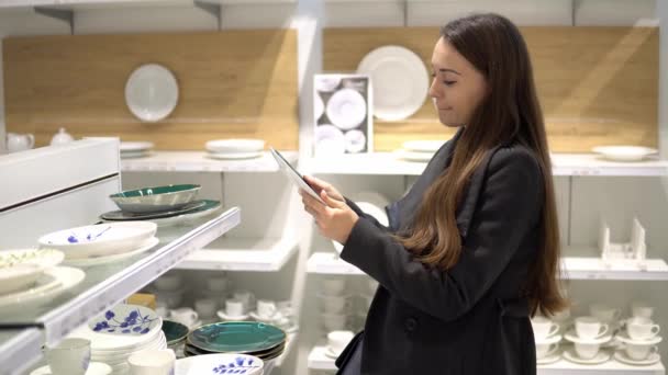Красивая женщина выбирает посуду в магазине супермаркета — стоковое видео
