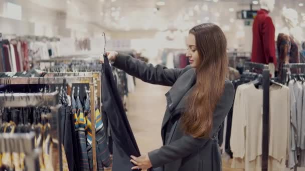 Jovem mulher bonita encontrar-se novas roupas em um supermercado loja — Vídeo de Stock