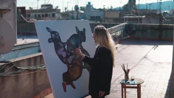 Молодая женщина рисует на крыше дома — стоковое видео