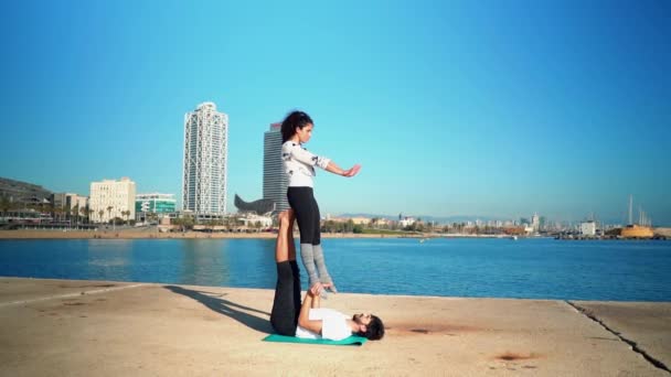 Прекрасная пара практикующая акро-йогу по утрам — стоковое видео