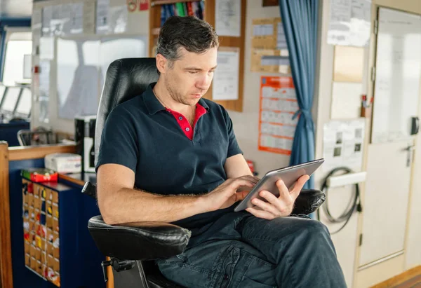 chief officer on navigation bridge watching digital tablet.