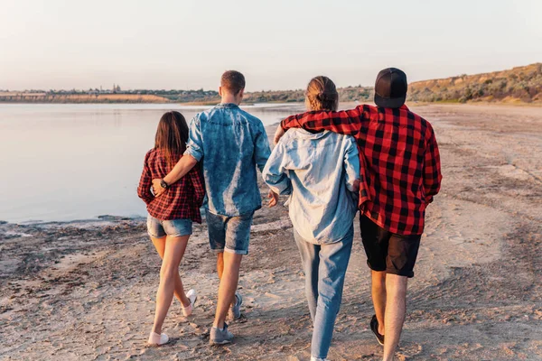 Amigos en la playa juntos caminando al atardecer — Foto de Stock