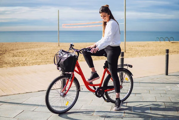 Жінка їде на велосипеді уздовж пляжного піску в літній час — стокове фото