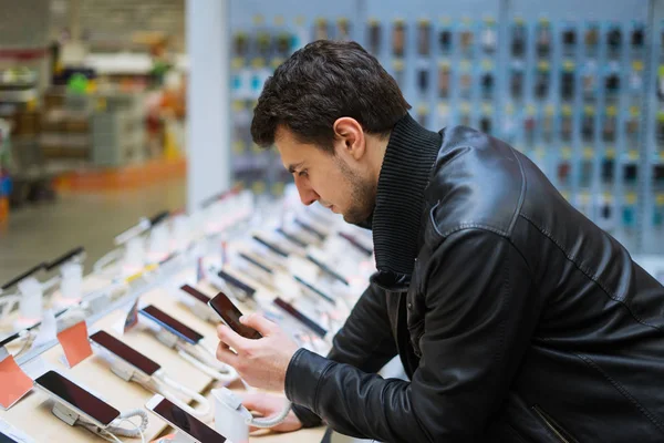 Joven cliente masculino elegir el teléfono inteligente en la tienda de teléfonos móviles — Foto de Stock