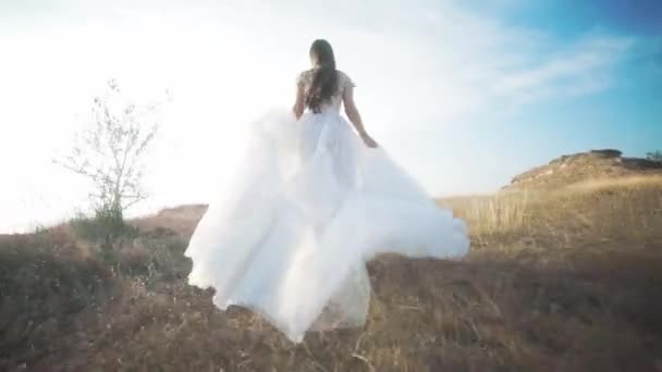 Τρέχοντας νύφη στο εκπληκτικό μακρύ φόρεμα μέσα στο τοπίο. — Αρχείο Βίντεο
