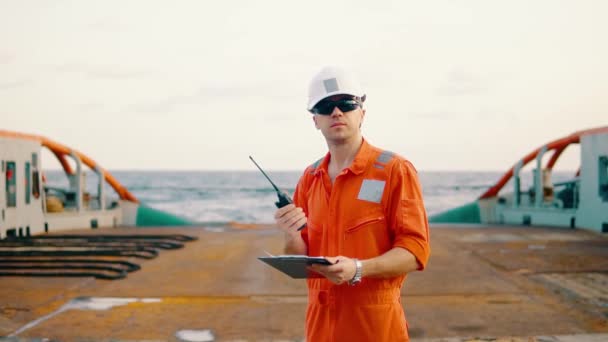 Deck Officer on deck of offshore vessel holds VHF walkie-talkie radio — Stock Video