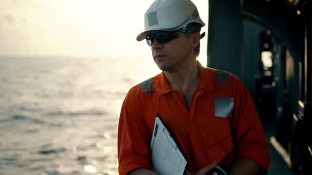 Deck Officer on deck of offshore vessel holds VHF walkie-talkie radio — Stock Video