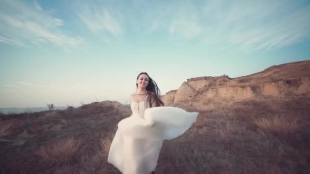 Lopende bruid in geweldige lange jurk door het landschap. — Stockvideo