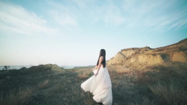 Lopende bruid in geweldige lange jurk door het landschap. — Stockvideo