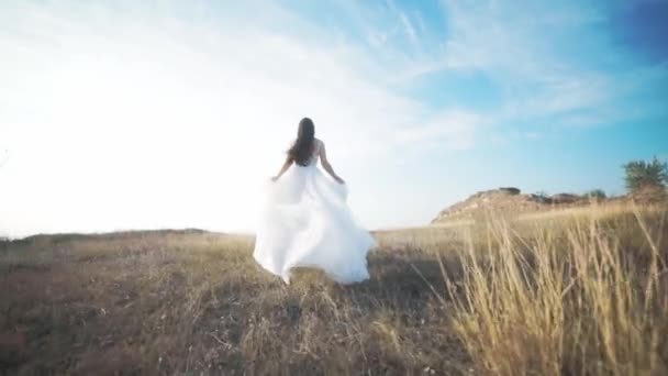 Running bride in amazing long dress through the landscape.