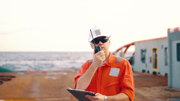 Zeevaartkundig scheepsofficier op het dek van offshore vaartuig bezit walkie-talkie marifoon — Stockvideo