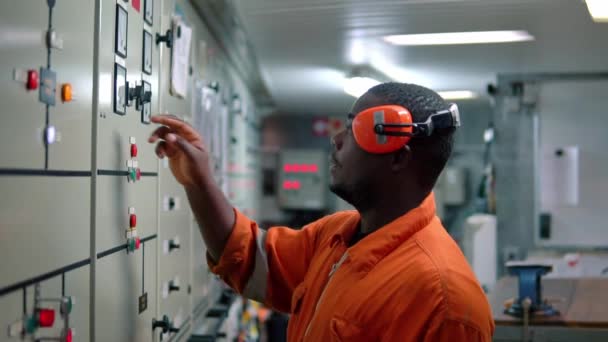 African Marine engineer officer in de motor controlekamer ECR. — Stockvideo