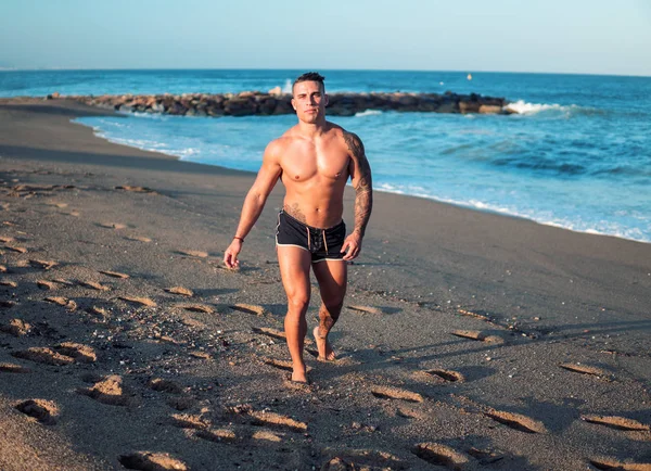 Wytatuowany kulturysta sexy męski trener na plaży. — Zdjęcie stockowe