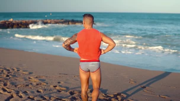 Tattooed bodybuilder sexy male coach at the beach. — Stock Video