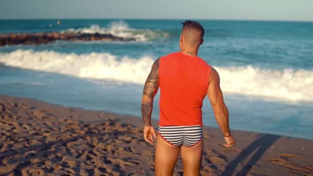 Tattooed bodybuilder sexy male coach at the beach. — Stock Video
