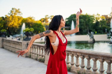 Ladyboy dövmeli transseksüel modeli yeşil parkta dans ediyor