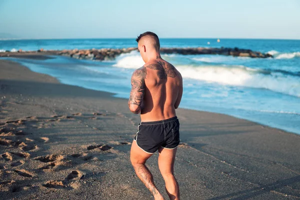 Wytatuowany kulturysta sexy męski trener na plaży. — Zdjęcie stockowe